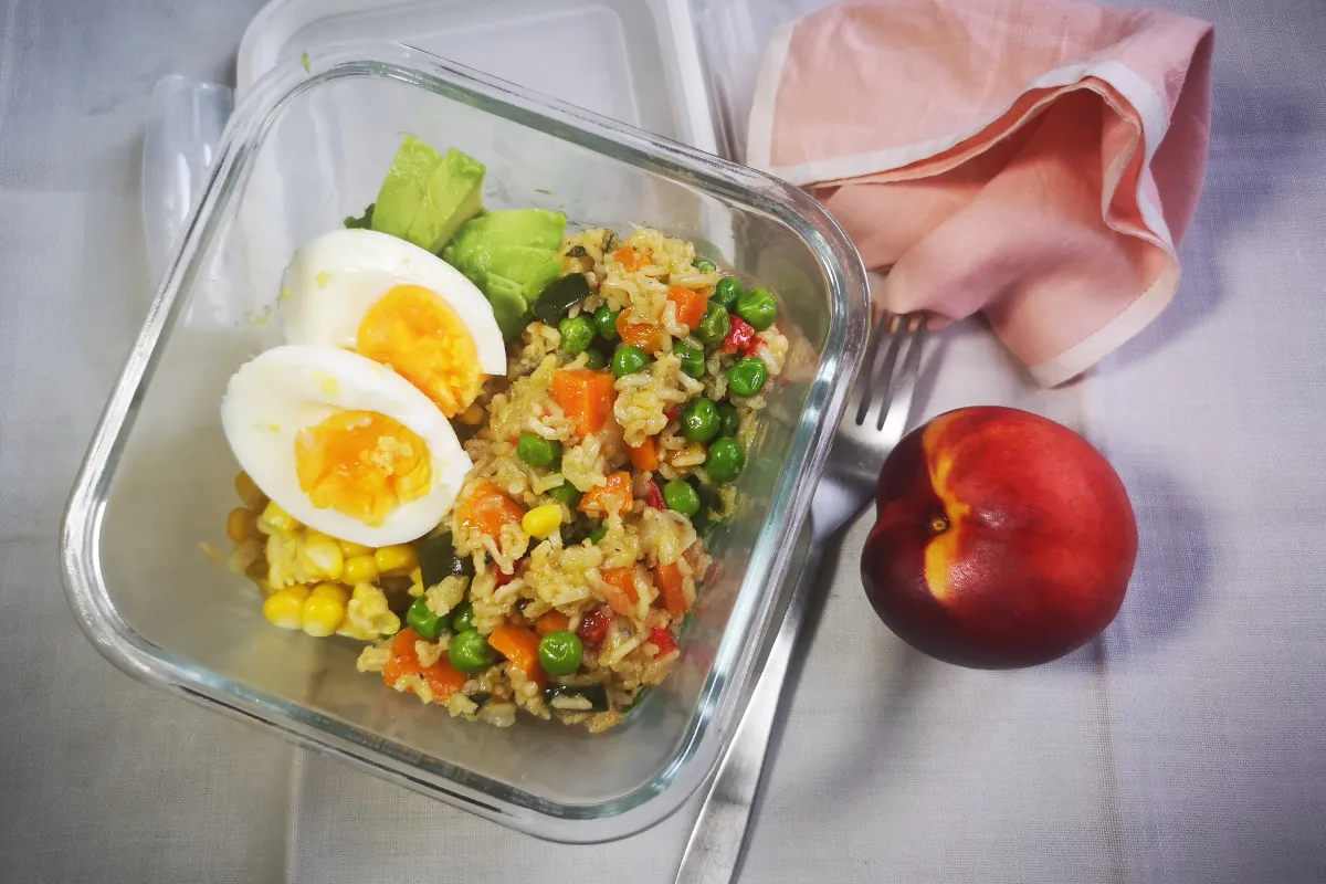 Arroz integral salteado con verduras variadas (pimiento, zanahoria, calabacín, guisantes), plato completo rico en fibra