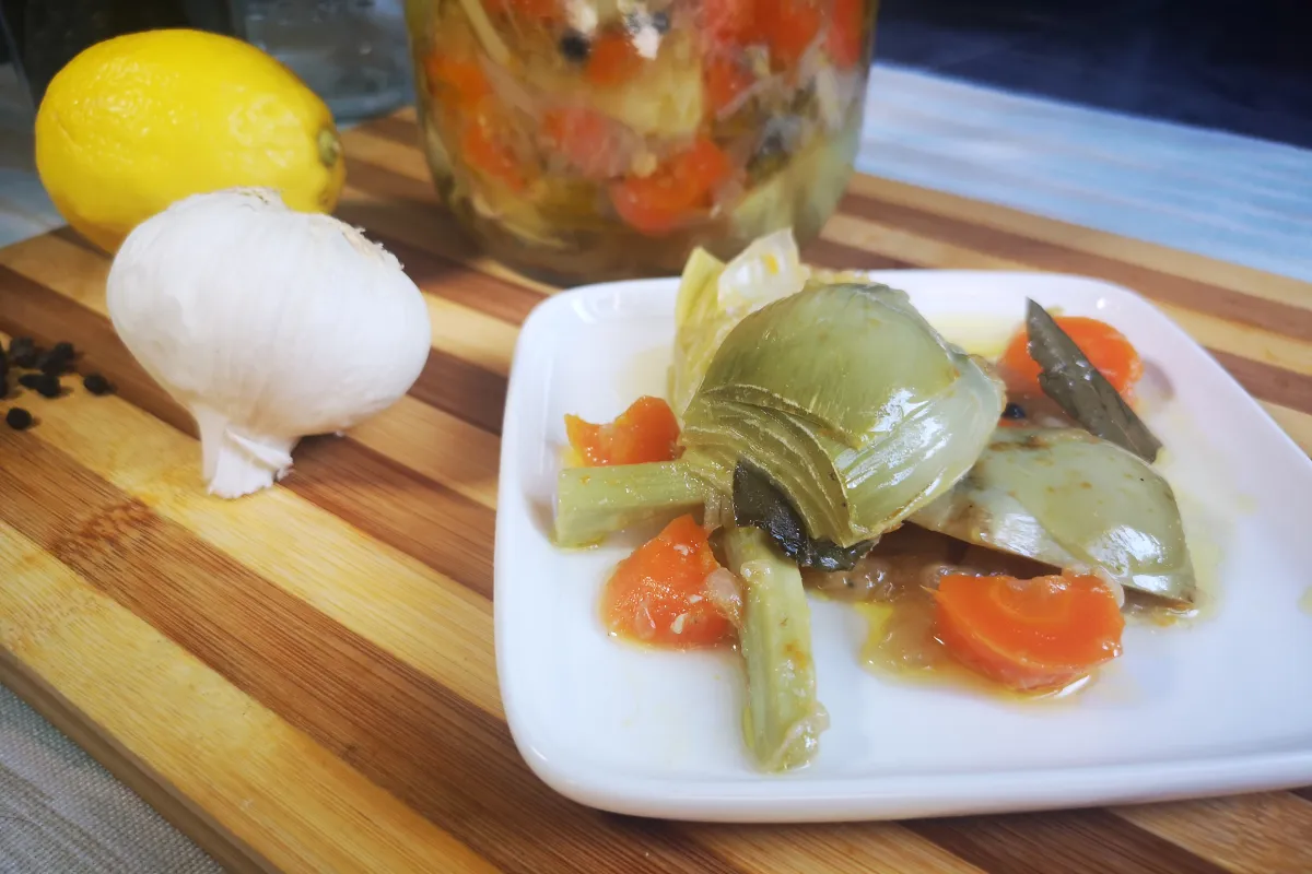 Alcachofas al escabeche con zanahoria, cebolla y especias en frasco de vidrio, conserva casera de temporada