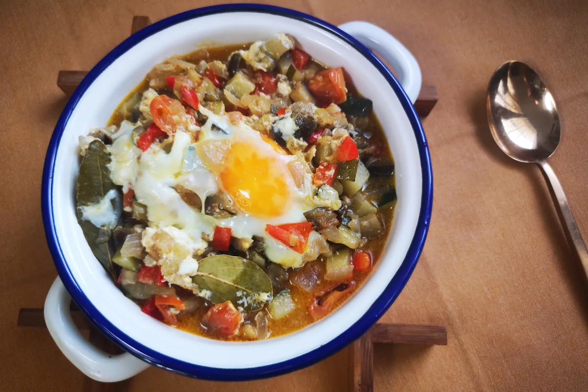 Huevo pochado con yema líquida sobre verduras estofadas de calabacín, berenjena, pimiento y tomate cherry
