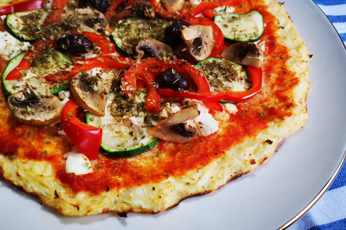 Pizza saludable con masa de coliflor rallada, tomate, queso fresco y vegetales al horno