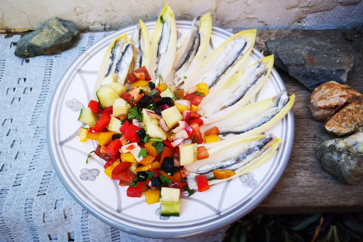 Hojas de endivia rellenas de pipirrana andaluza con boquerones en vinagre, aperitivo mediterráneo fresco rico en omega-3