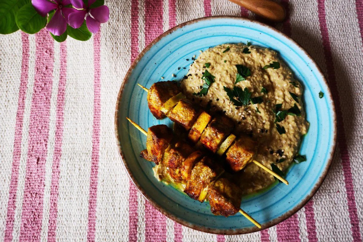 Brochetas de pollo con lima y limón sobre hummus cremoso de lentejas, plato proteico completo saludable