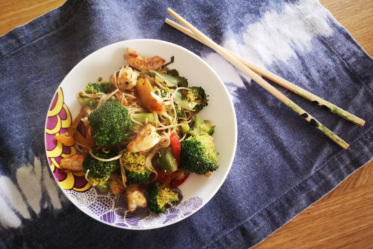 Fideos de arroz salteados con langostinos y verduras en wok, plato asiático sin gluten rico en proteína