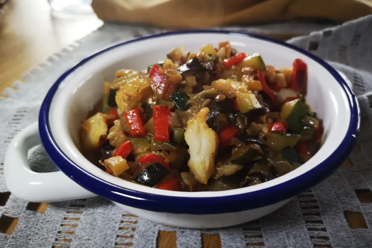 Pisto casero con cebolla, pimiento, calabacín, berenjena y bacalao jugoso, receta saludable mediterránea